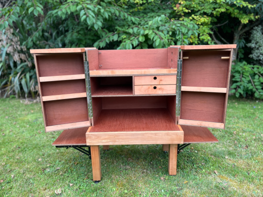 So much storage! Wooden cabinet with open doors and shelves, resting on a green lawn.